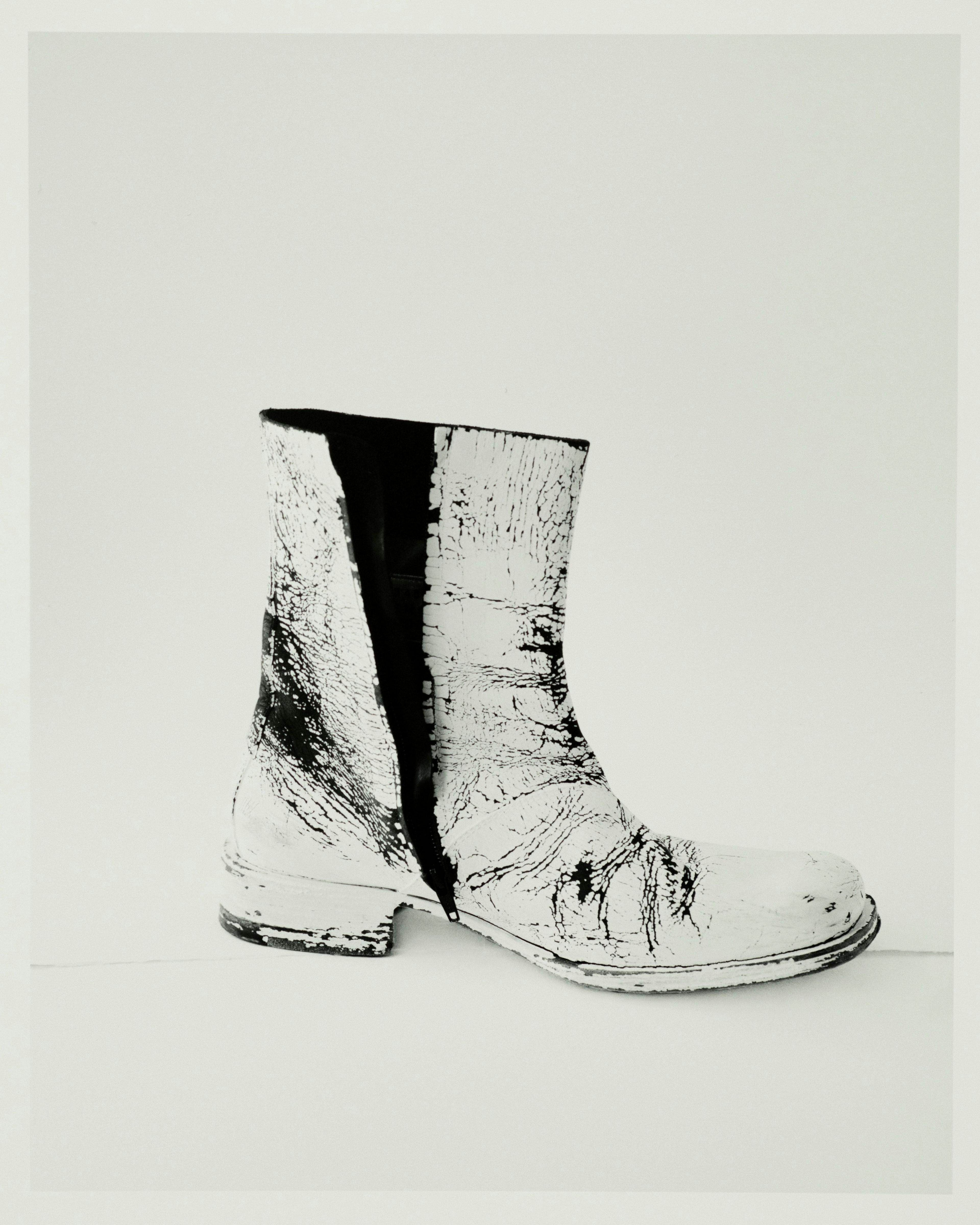 Vintage boots by Maison Martin Margiela, Spring 1999, from Artifact. Having first appeared as a prototype at the Spring 1999 show, these boots, with their cracked paint finish, reflect Martin Margiela's deconstructionist approach. The designer avoided interviews about his collections to allow room for multiple interpretations.