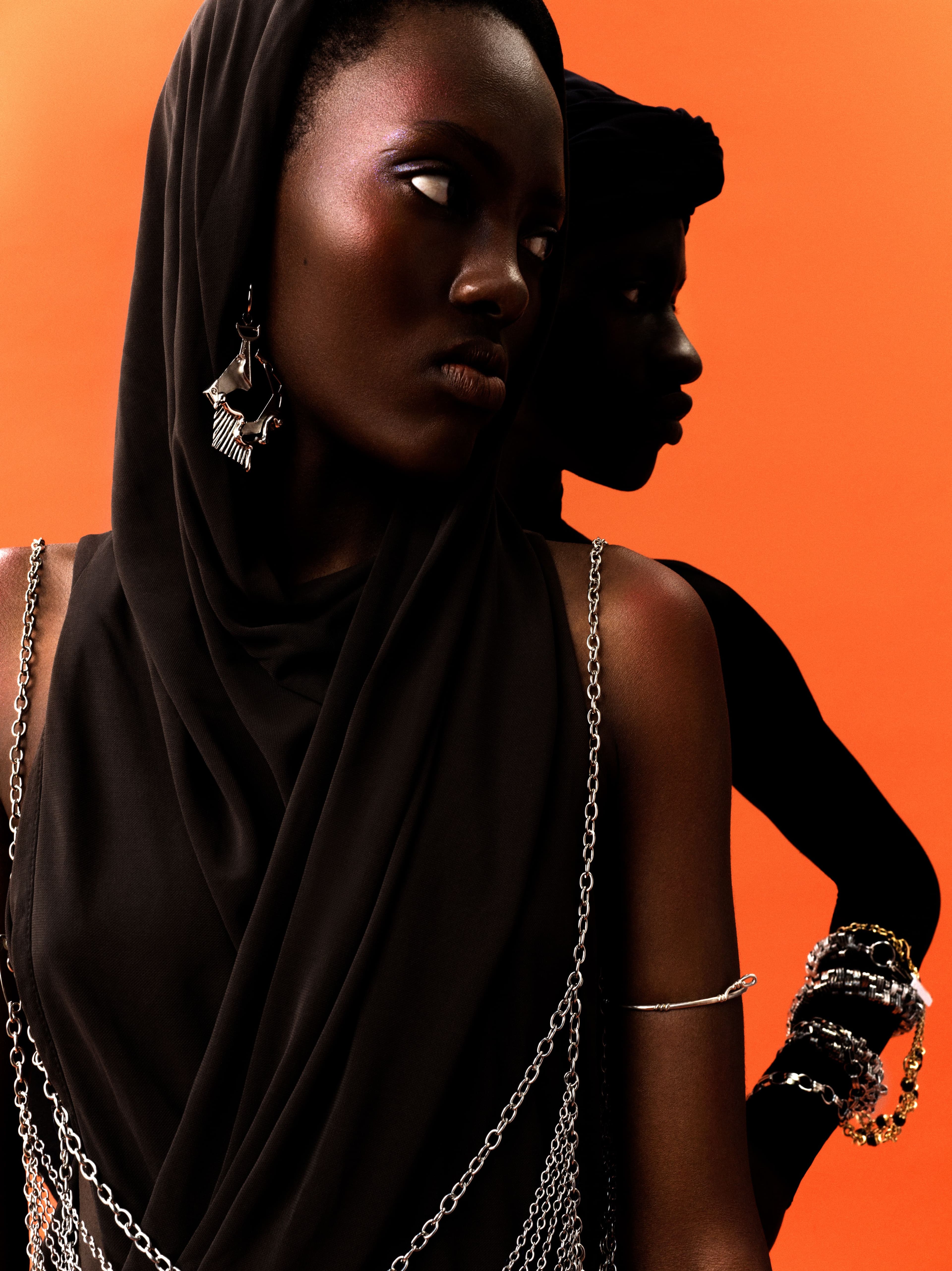 From left, Teline wears dress by Saint Laurent. Bra, necklace, and earring by G6C. Mohamadou wears headpiece and all jewelry by Chanel.